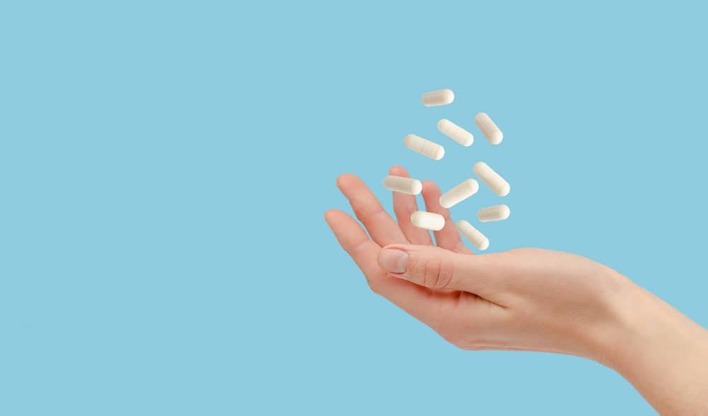 white-pills-floating-female-hand-isolated-blue-healthcare-treatment-concept-copy-space-1